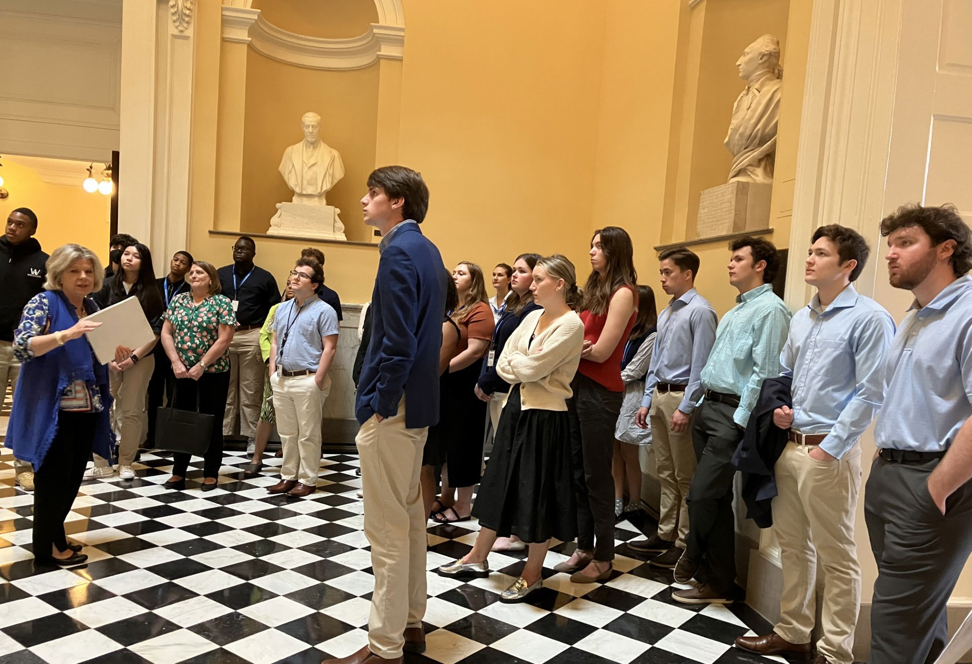 Một nhóm người đang đứng trước một bức tượng